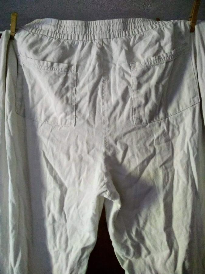 off white linen pants hanging on clothesline. almost imperceptible wear on the crotch/seat.