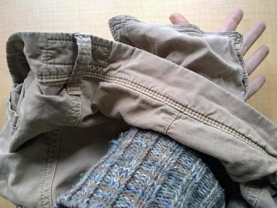 Waist/pocket of khaki pants, with hand inside pocket and fingers extending out to show that the pocket had a hole in it
