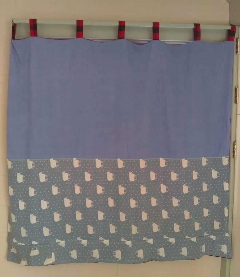 Curtain (hanging in window) made from 3 fabrics: sheep print, blue, and red plaid loops