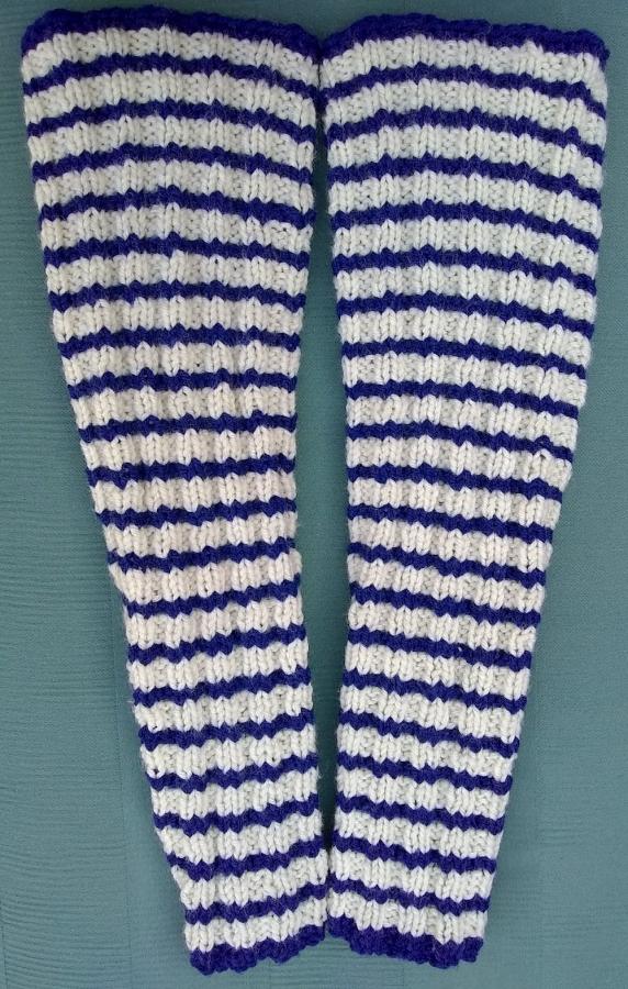 blue and white striped hand-knit arm warmers on a green background