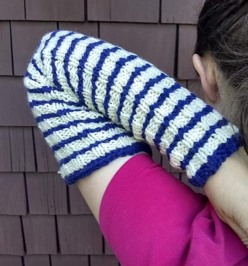 woman doing arm stretch from back, wearing blue and white striped arm warmers and pink shirt, only one arm visible