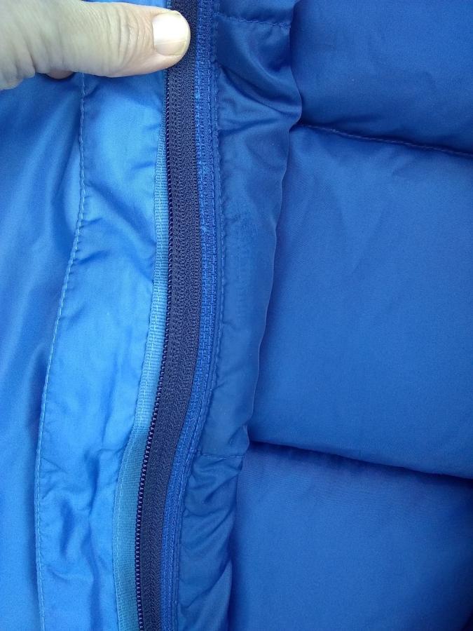 Detail of blue puffy vest, showing underside of navy zipper